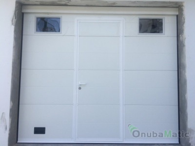 Puerta automática seccional lacada blanca Mod. Liso Unicanal con puerta peatonal instalada en Moguer.