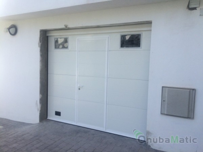 Puerta automática seccional lacada blanca Mod. Liso Unicanal con puerta peatonal y ventanas  instalada en Moguer.