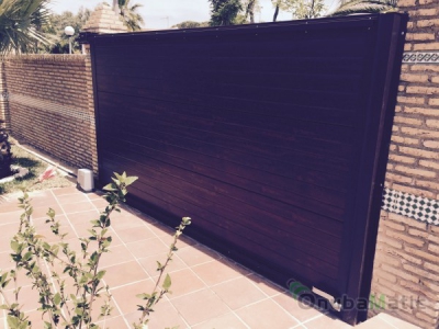 Puerta corredera de panel sweccional con masrcos de aluminio imitación madera instalada en Punta Umbria (Huelva).