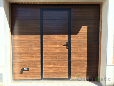 Puerta seccional automática imitacion madera con ventanas en vivienda unifamiliar en Beas.