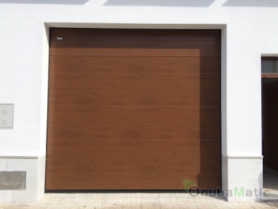 Puerta seccional automática imitacion madera con ventanas en vivienda unifamiliar en Moguer