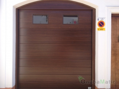 Puerta seccional automática imitacion madera con ventanas instalada en vivienda unifamiliar en Moguer
