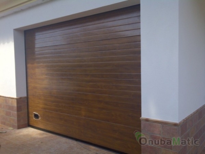 Puerta seccional automática imitacion madera en vivienda unifamiliar en El Portil.