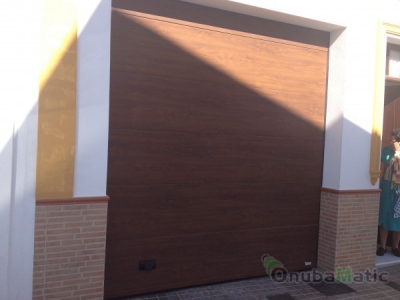 Puerta seccional imitación madera en vivienda en Moguer.