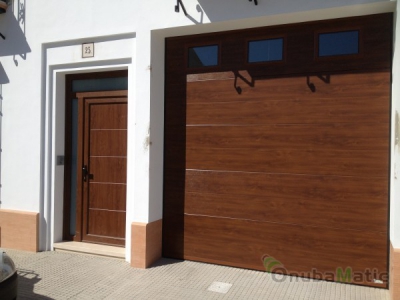 Puerta seccional imitación madera tablero liso con puerta PVC del mismo color. Instalación vivenda unifamiliar en Moguer